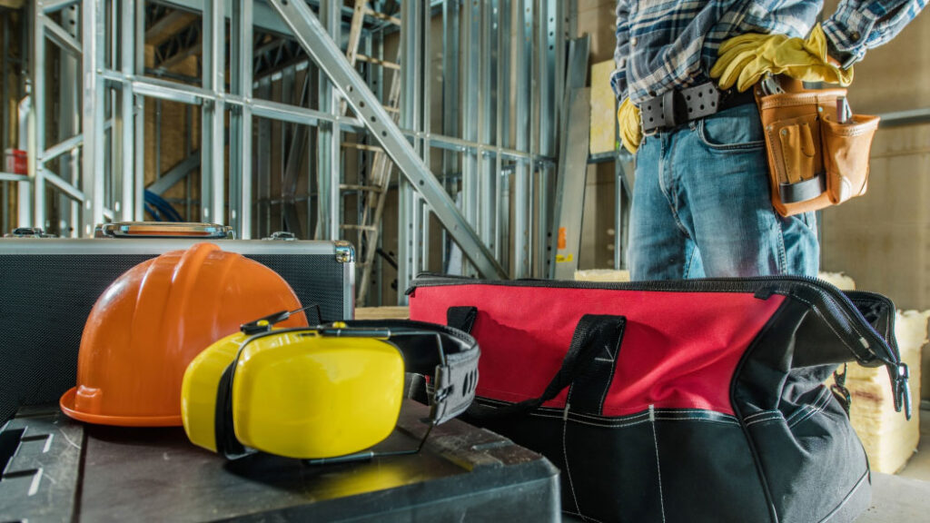 Safety equipment including a hard hat, ear protection, and tool bag, symbolizing the importance of personal protective equipment (PPE) in job hazard analysis through compliance and risk mitigation system.