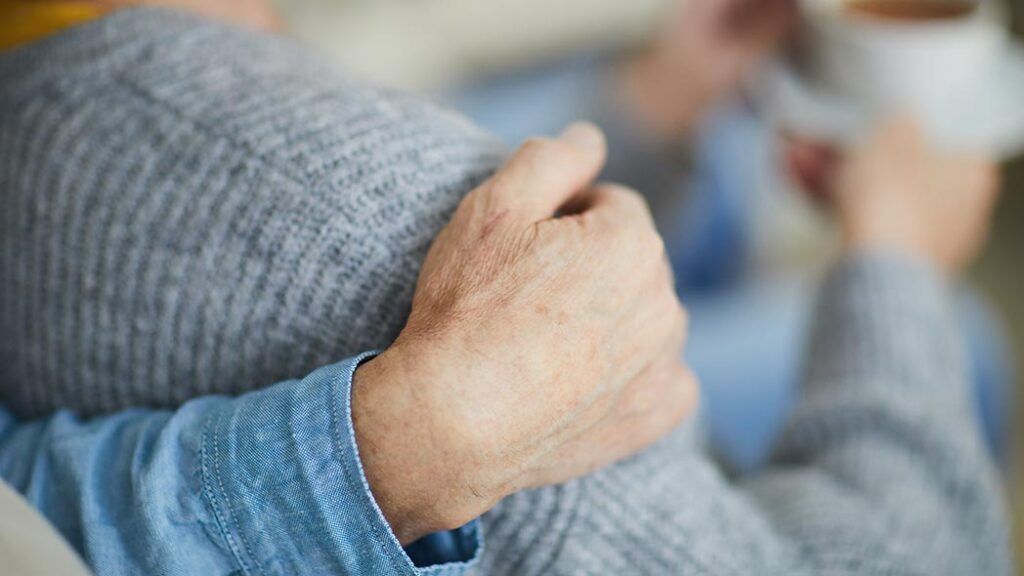 Support being given to a loved one who is going through a very tough time, by putting their hand over their shoulder.