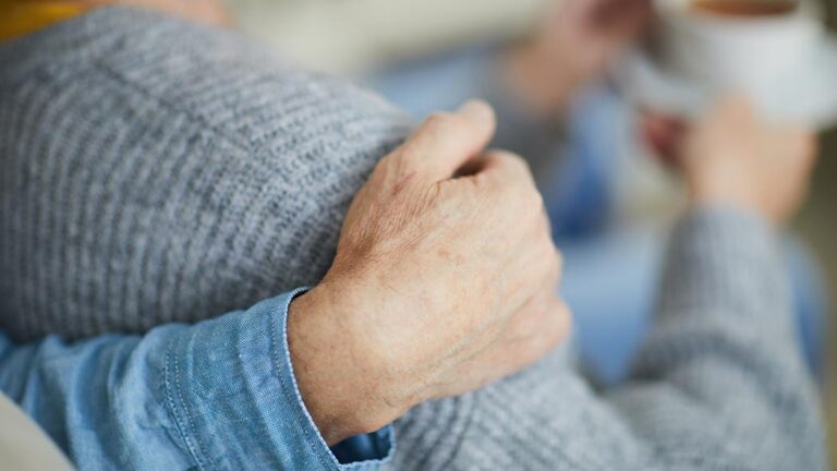 Support being given to a loved one who is going through a very tough time, by putting their hand over their shoulder.