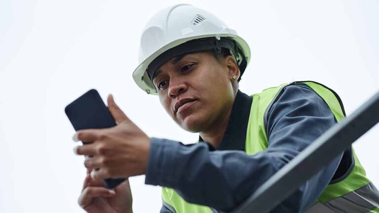 A frontline worker using a digital device with HSEQ software to ensure compliance of the site.