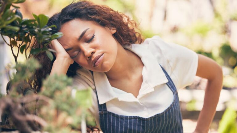 Sustainability fatigue being represented by an individual in a garden demonstrating tiredness.