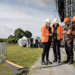 Contractors wearing orange high-vis during an HSA summer inspection campaign in Ireland, reviewing safety compliance, hazards, and controls at an outdoor event worksite.