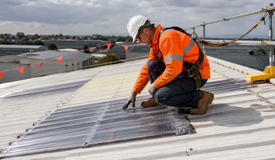 Building contractor inspecting fragile roof sheeting for work at height compliance